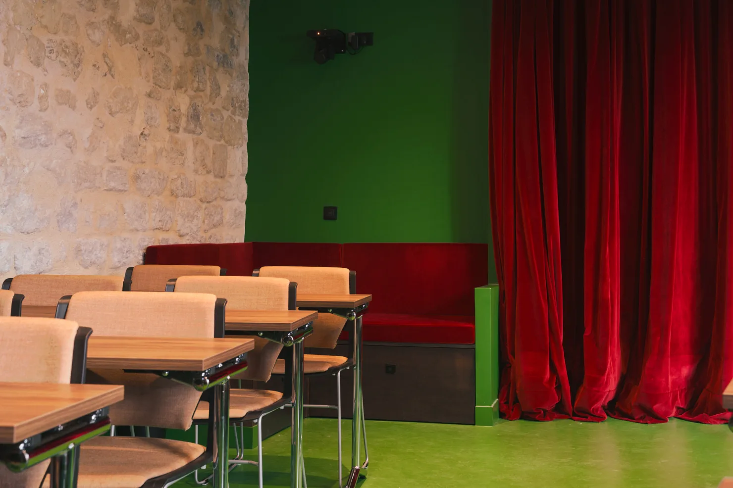 Le mur de pierre et le rideau de velours rouge, derrière les tables.