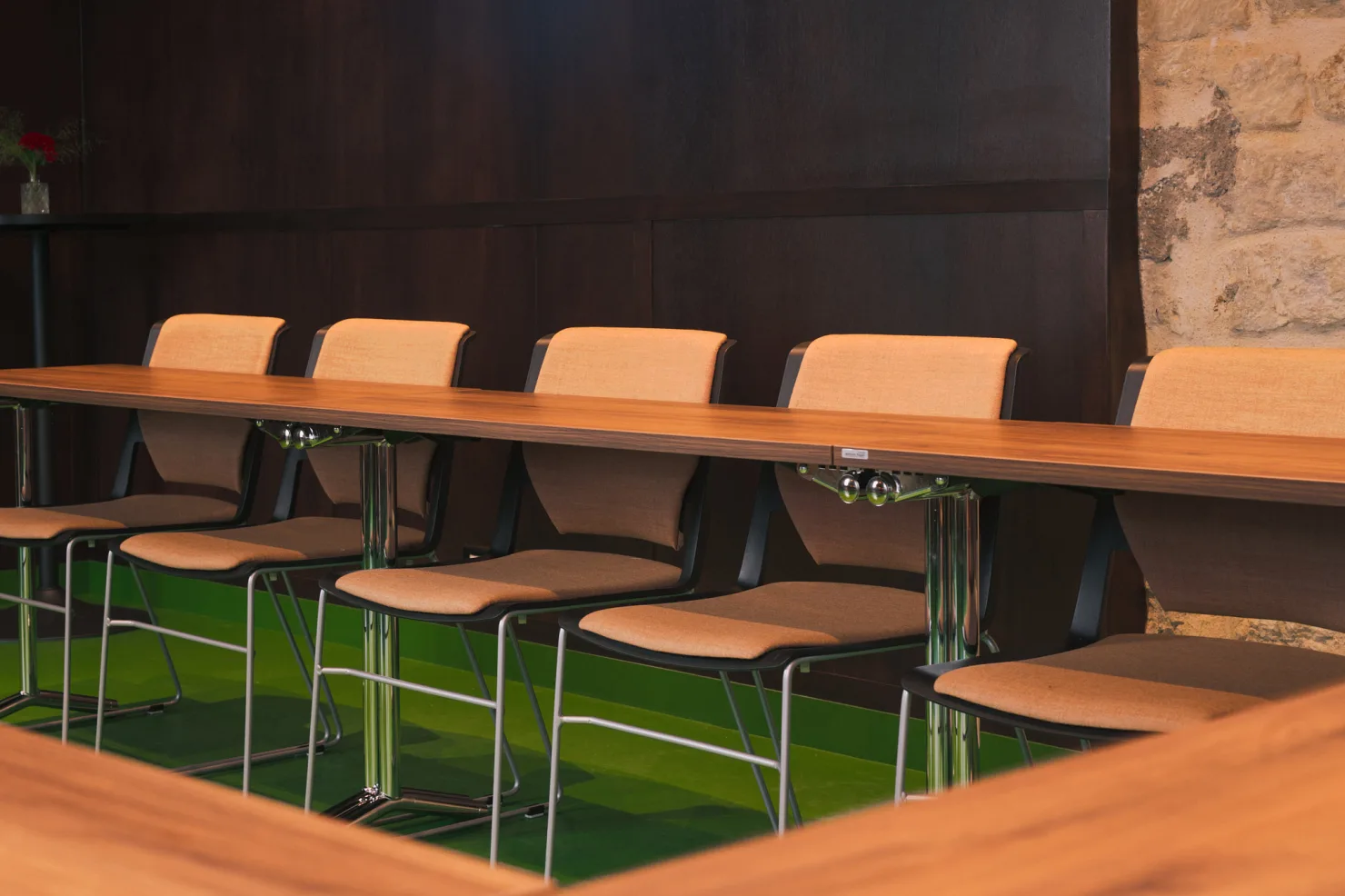 Les chaises tapissées le long de la table, contre la boiserie et le mur de pierre.