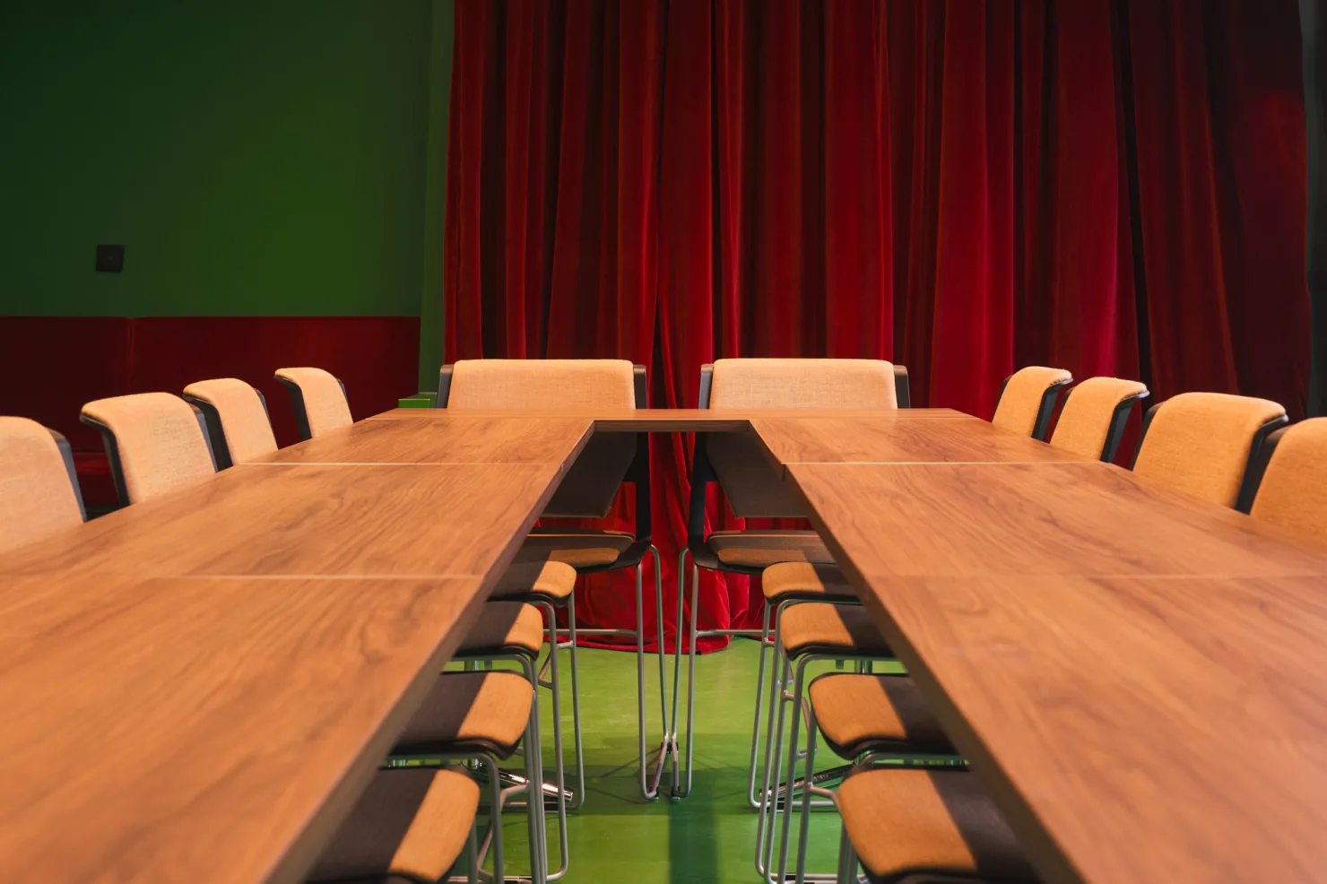 La table vue de son extrémité, ses chaises de part et d'autre, devant le rideau de velours rouge.