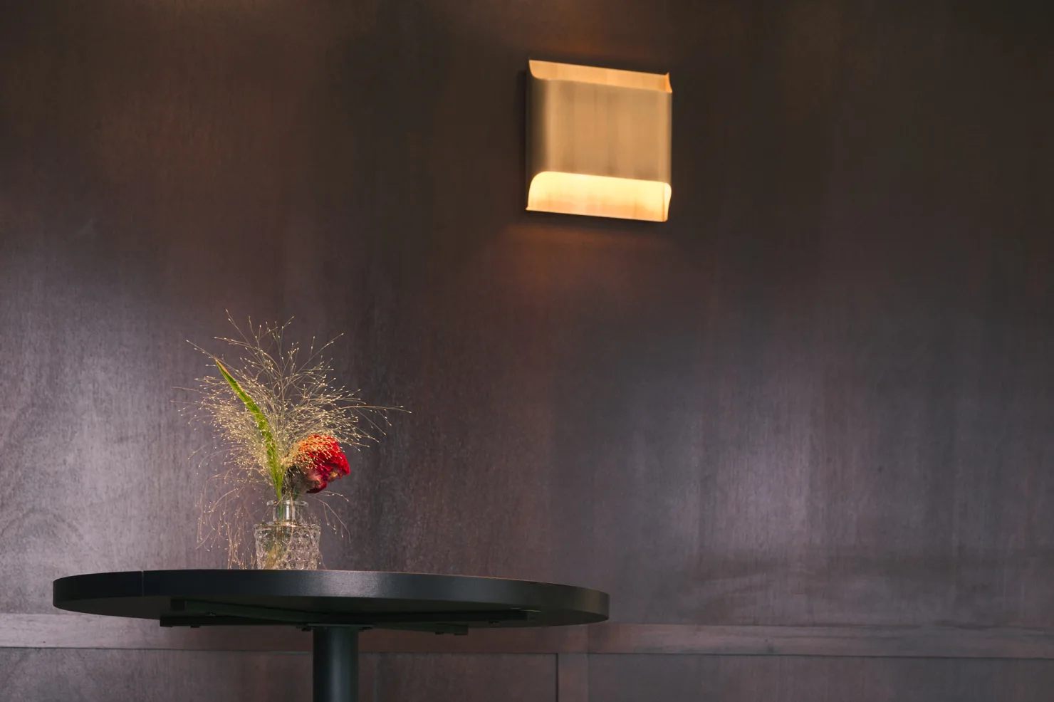 Une applique en laiton sur la boiserie sombre.